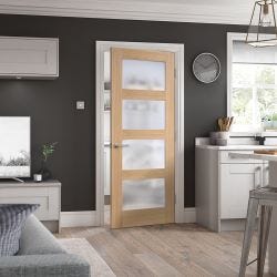 Wooden glazed door in a room with a grey sofa, white cabinets, a television and a clock. The room is painted dark grey