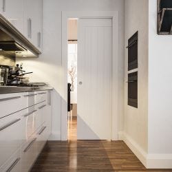 white pocket door in slightly messy kitchen, there are pots and pans on the countertops.